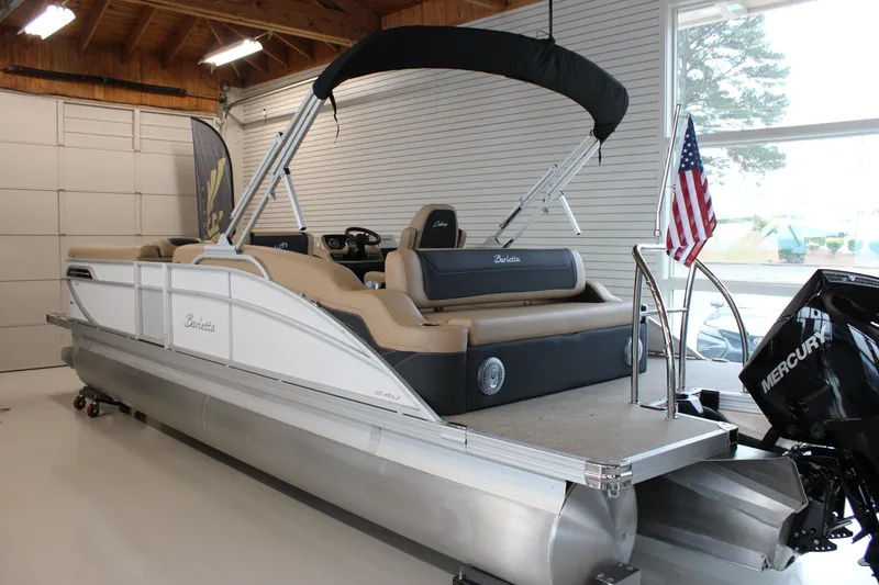 Slide: The Image of 2026 Barletta C24U pontoon boat in showroom, featuring Mercury engine and American flag. - 9