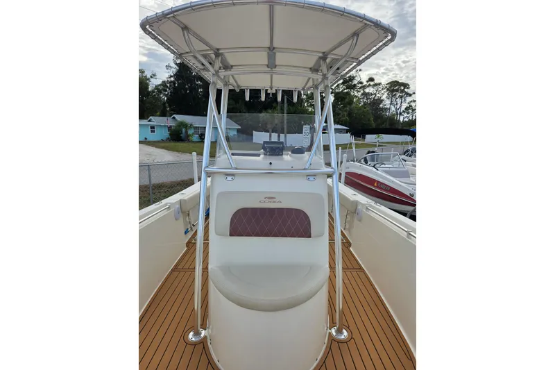 Slide: The Image of 2021 Cobia 237 Center Console boat with T-top and teak deck, docked outdoors. - 14