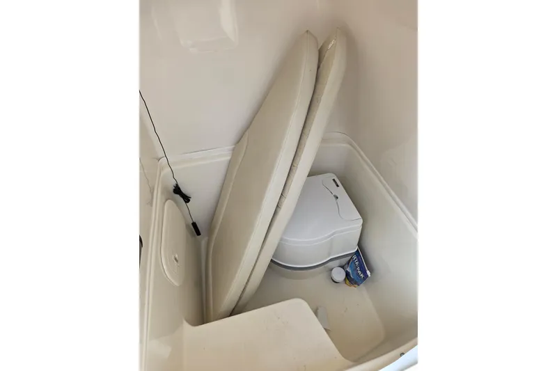 Slide: The Image of 2021 Cobia 237 Center Console boat interior with portable toilet and storage. - 16