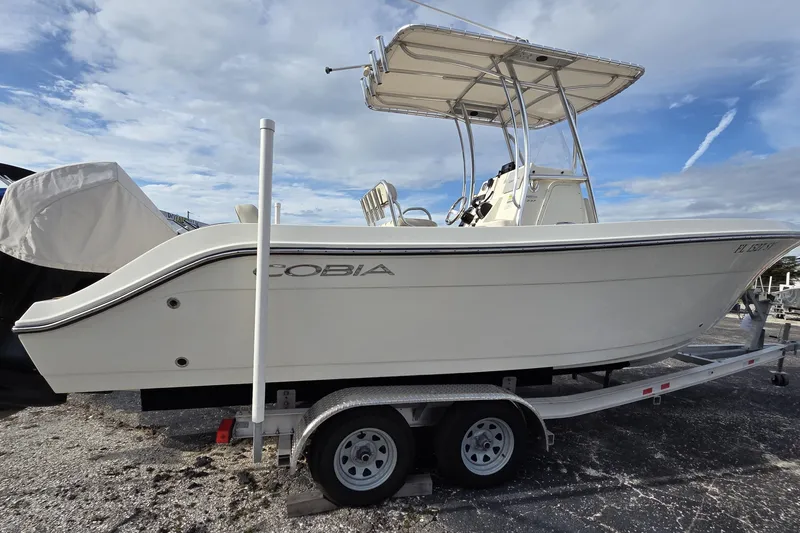 Slide: The Image of 2021 Cobia 237 Center Console boat on trailer under a cloudy sky. - 18
