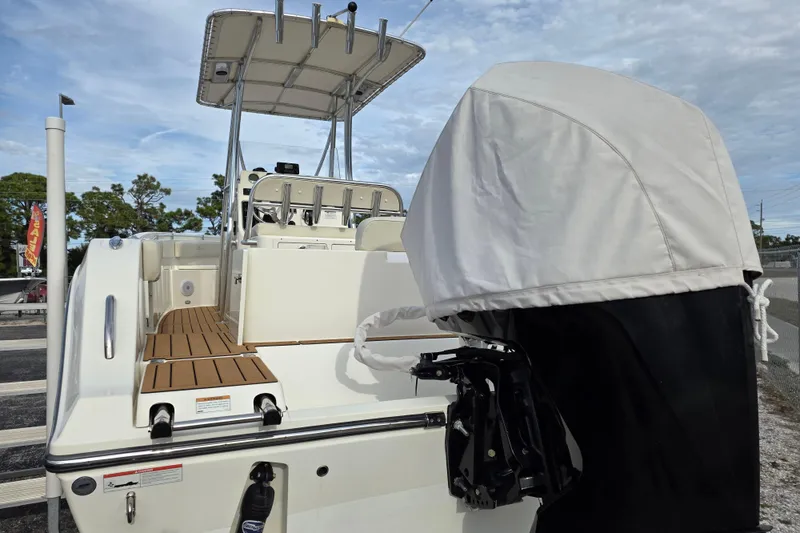 Slide: The Image of 2021 Cobia 237 Center Console boat with covered outboard motor, docked under cloudy sky. - 3