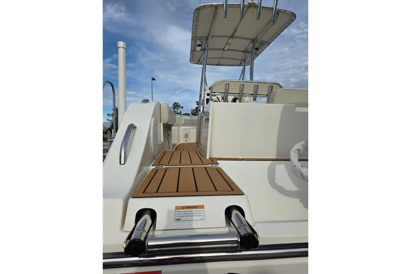 Slide: The Image of 2021 Cobia 237 Center Console boat deck with seating and canopy under blue sky. - 4