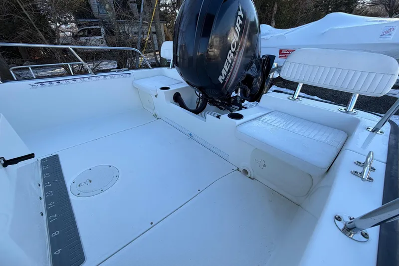 Slide: The Image of 2018 Boston Whaler 190 Montauk boat with seating and outboard motor, parked outdoors. - 11