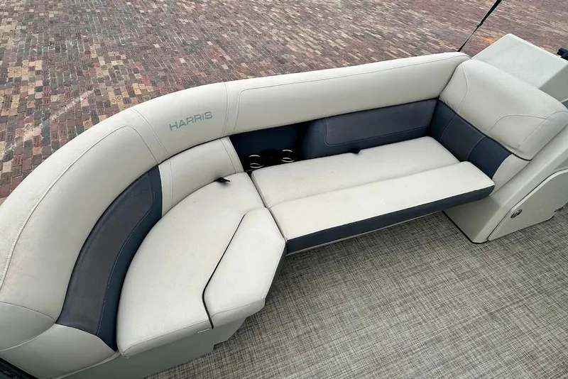 Slide: The Image of 2023 Harris Cruiser 230 boat seating with beige and gray upholstery on a textured deck. - 17