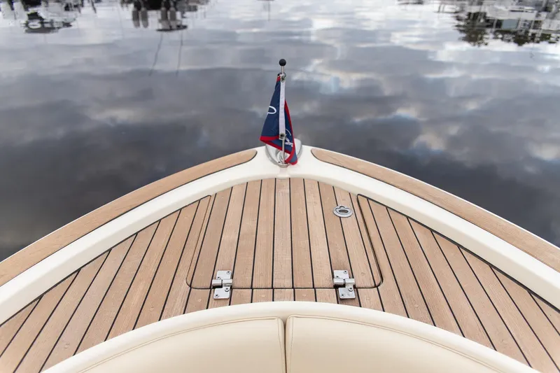 Slide: The Image of 2016 Chris-Craft Catalina 26 boat deck with wooden finish and flag, reflecting on water. - 9
