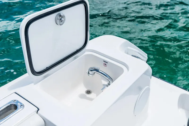 Slide: The Image of 2026 Edgewater 325CC boat sink with open lid, surrounded by clear blue water. - 19