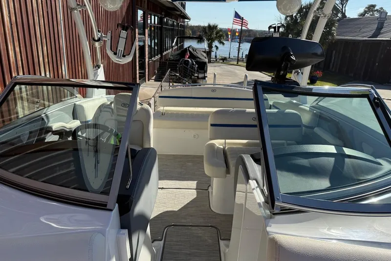 Slide: The Image of 2021 Cobalt R3 Surf boat interior with seating and steering wheel, docked near a waterfront. - 14