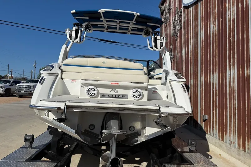 Slide: The Image of 2021 Cobalt R3 Surf boat on trailer, rear view, near rustic building. - 2