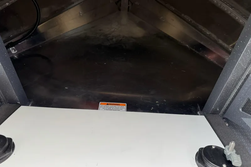 Slide: The Image of Interior view of 2026 Duckworth 24 Pacific Pro boat, featuring metal flooring and warning label. - 36