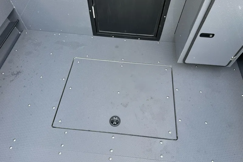 Slide: The Image of Interior deck of 2026 Duckworth 24 Pacific Pro boat, featuring storage hatch and door. - 43