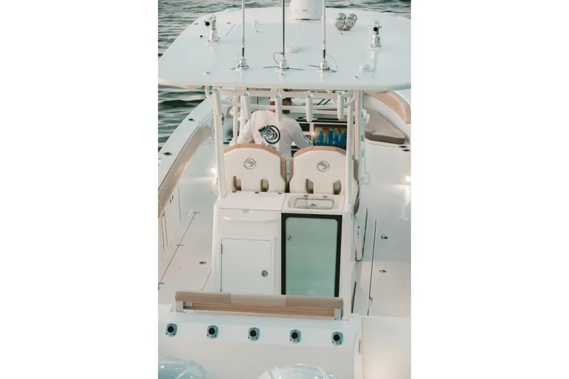 Slide: The Image of 2026 Edgewater 340CC boat interior with helm station and seating, on calm water. - 19