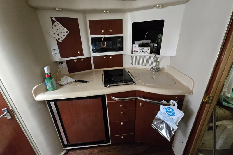 Slide: The Image of 1998 Sea Ray 340 Amberjack boat kitchen with sink, stove, and storage cabinets. - 26