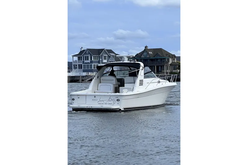 Slide: The Image of 1998 Sea Ray 340 Amberjack boat on water near coastal homes. - 3