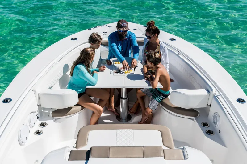 The Image of Family enjoying a meal on a 2026 Edgewater 370CC boat in clear turquoise waters. - 1
