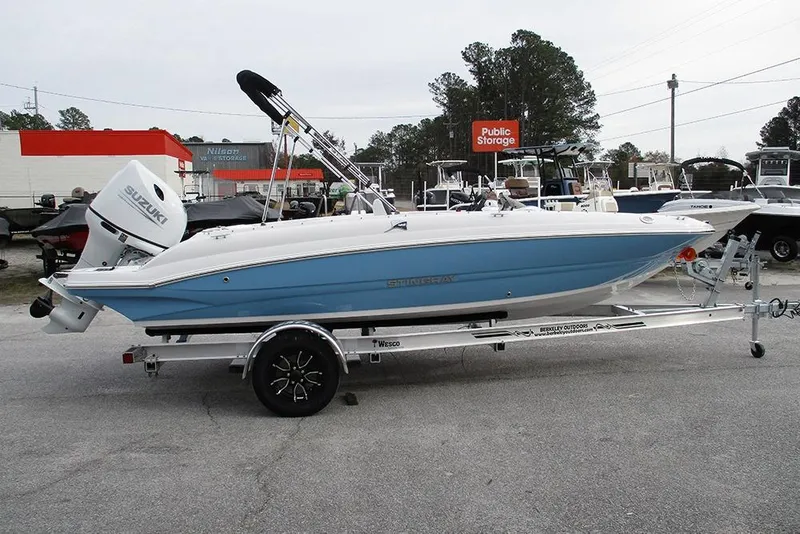 The Image of 2026 Stingray 182 SC boat on trailer, featuring Suzuki outboard motor, parked outdoors. - 1
