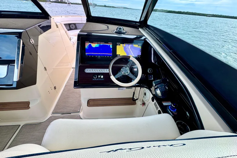 Slide: The Image of 2021 Chris-Craft Calypso 35 helm with navigation screens, steering wheel, and ocean view. - 25