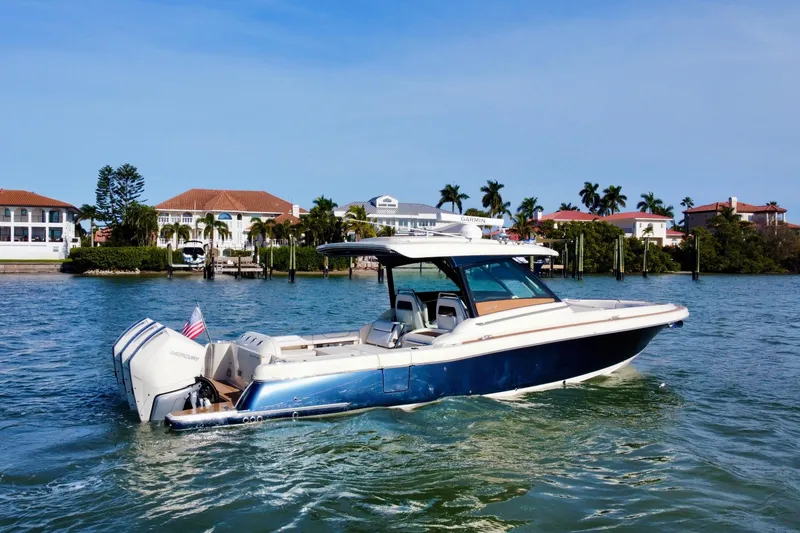 Slide: The Image of 2021 Chris-Craft Calypso 35 boat cruising near waterfront homes, clear blue sky. - 5