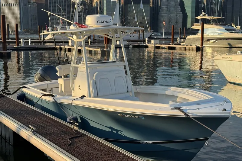 Slide: The Image of 2019 Regulator 23 boat docked in urban marina with city skyline backdrop. - 2