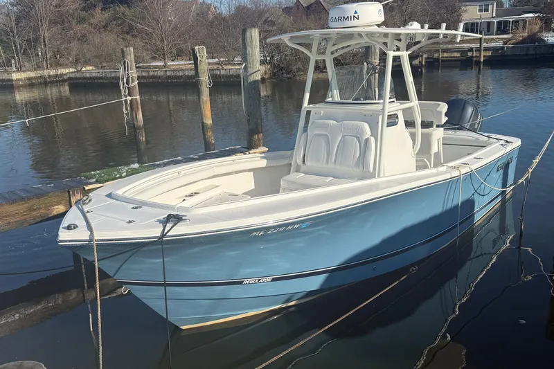 Slide: The Image of 2019 Regulator 23 boat docked in calm waters, featuring a blue hull and Garmin equipment. - 32