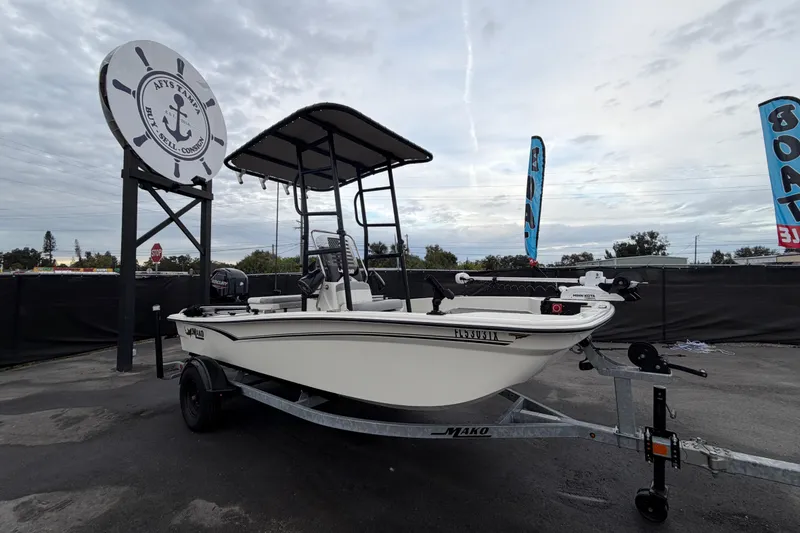 Slide: The Image of 2024 Mako Pro Skiff 15 CC boat on trailer at dealership, cloudy sky background. - 0