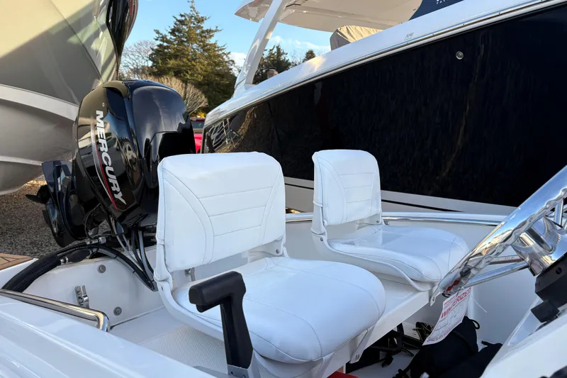 Slide: The Image of 2023 Boston Whaler 130 Super Sport boat with Mercury engine, featuring cushioned seating. - 2
