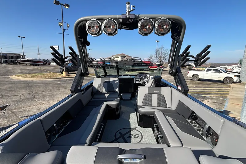 Slide: The Image of 2022 MasterCraft X26 boat interior with seating and speakers, parked outdoors. - 16