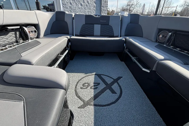 Slide: The Image of 2022 MasterCraft X26 boat interior with gray seating and logo on carpet. - 19