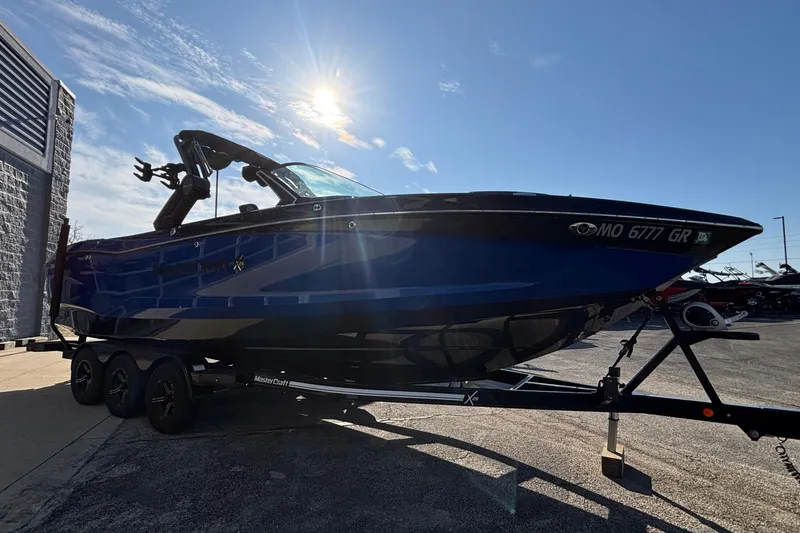 Slide: The Image of 2022 MasterCraft X26 boat on trailer under bright sun. - 3