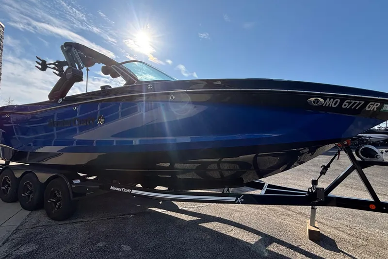 Slide: The Image of 2022 MasterCraft X26 boat on trailer under bright sunlit sky. - 4