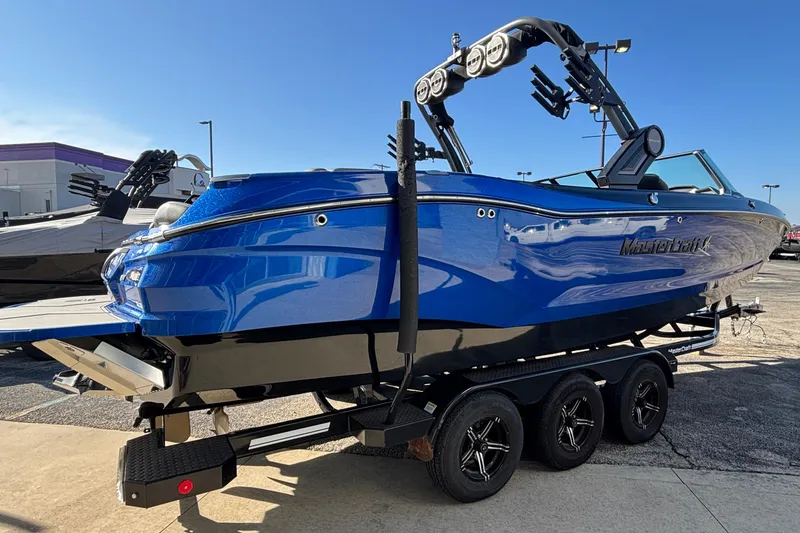 Slide: The Image of 2022 MasterCraft X26 boat in vibrant blue on a trailer, parked outdoors. - 5