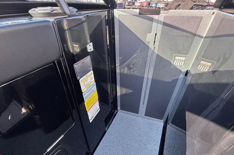 Slide: The Image of Interior view of a 2022 MasterCraft X26 boat, featuring sleek black panels and safety labels. - 54