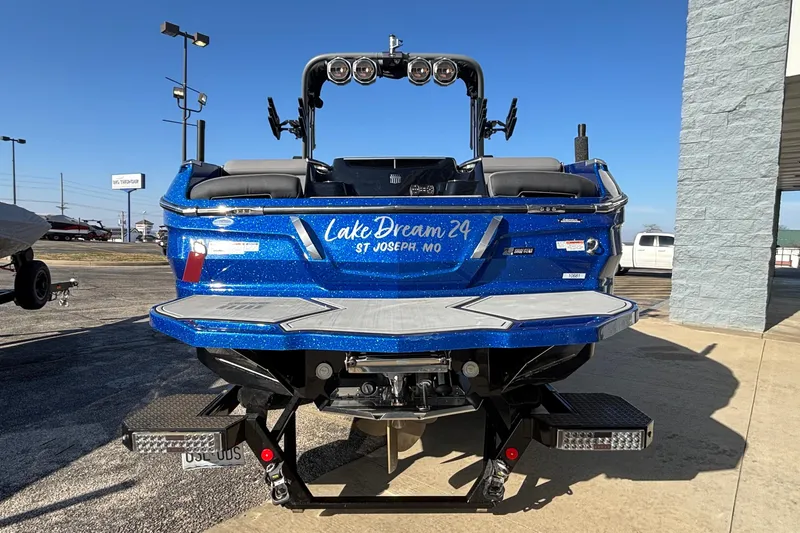 Slide: The Image of 2022 MasterCraft X26 boat in blue, rear view, parked outdoors. - 6