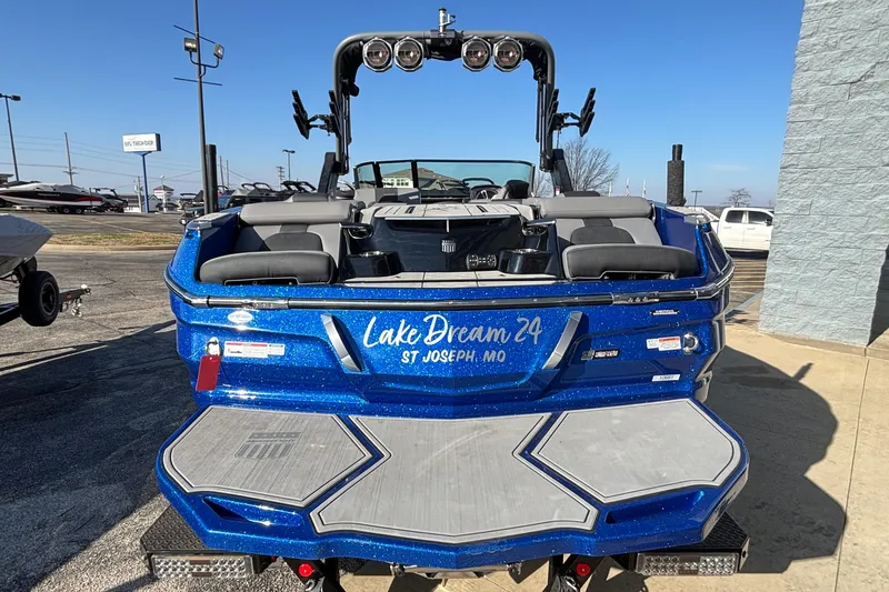 Slide: The Image of 2022 MasterCraft X26 boat in blue, rear view, parked outdoors. - 7