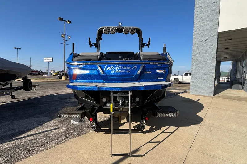 Slide: The Image of 2022 MasterCraft X26 boat in blue, parked outdoors with visible ladder and signage. - 81