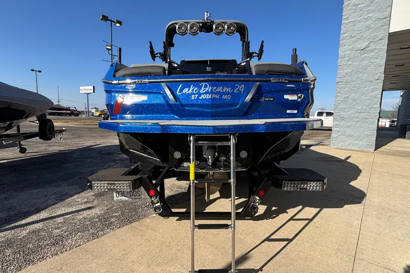 Slide: The Image of 2022 MasterCraft X26 boat, blue, rear view, parked outdoors, sunny day. - 82
