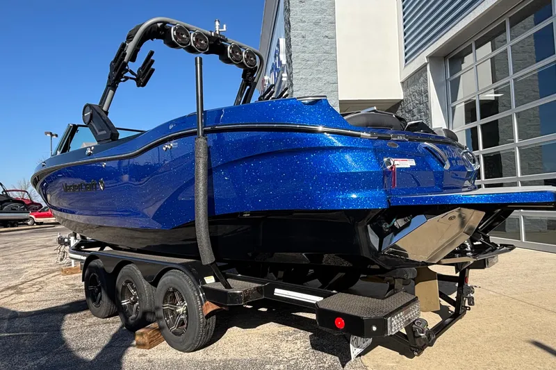 Slide: The Image of 2022 MasterCraft X26 boat in vibrant blue on a trailer, parked outdoors. - 83