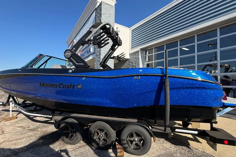 Slide: The Image of 2022 MasterCraft X26 boat in vibrant blue on a trailer outside a showroom. - 85