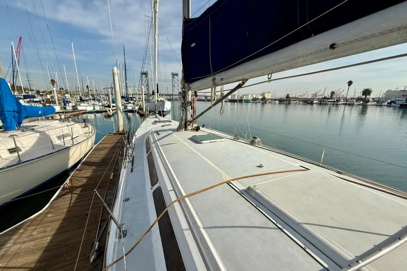 Slide: The Image of 1985 MacGregor 65 sailboat docked in a marina, surrounded by other boats. - 11