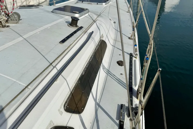 Slide: The Image of 1985 MacGregor 65 sailboat deck with rigging and fittings, docked on calm water. - 12