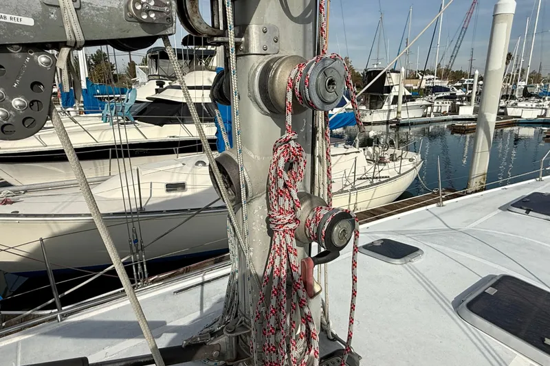 Slide: The Image of 1985 MacGregor 65 sailboat mast with ropes in a marina setting. - 13