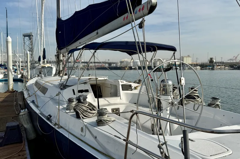 Slide: The Image of 1985 MacGregor 65 sailboat docked at marina, featuring sleek design and spacious deck. - 2