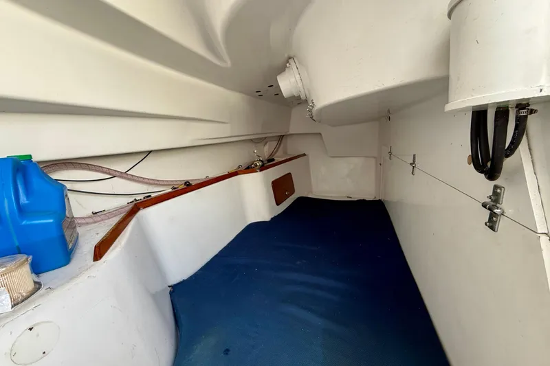 Slide: The Image of Interior of a 1985 MacGregor 65 sailboat, featuring storage space and blue flooring. - 20