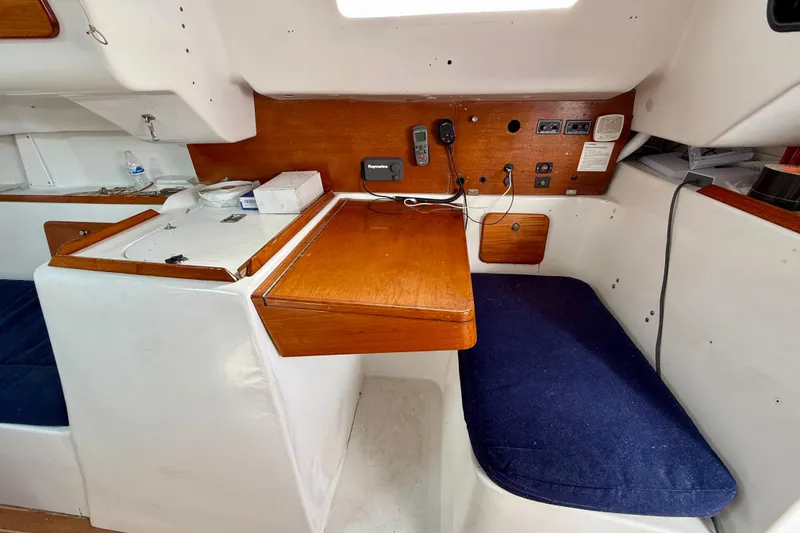 Slide: The Image of Interior of 1985 MacGregor 65 sailboat with wooden table and blue seating. - 22