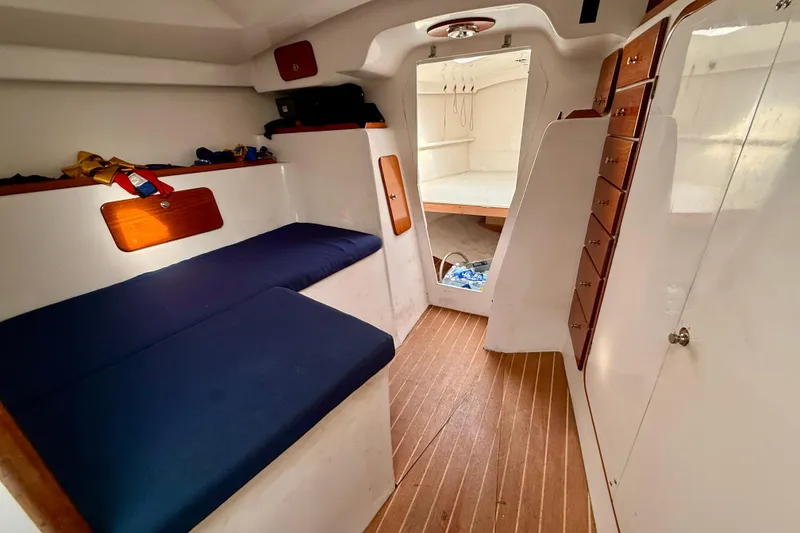 Slide: The Image of Interior of a 1985 MacGregor 65 sailboat with blue cushions and wooden accents. - 26