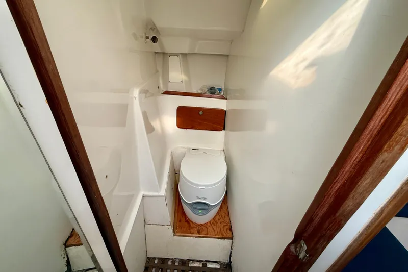 Slide: The Image of Compact bathroom in 1985 MacGregor 65 sailboat with portable toilet and wooden accents. - 27