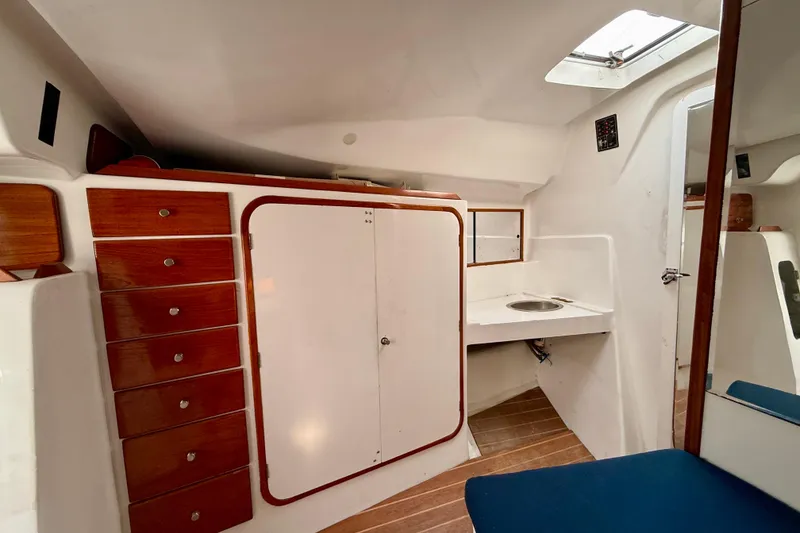 Slide: The Image of Interior of a 1985 MacGregor 65 sailboat with wooden cabinets and compact sink area. - 28