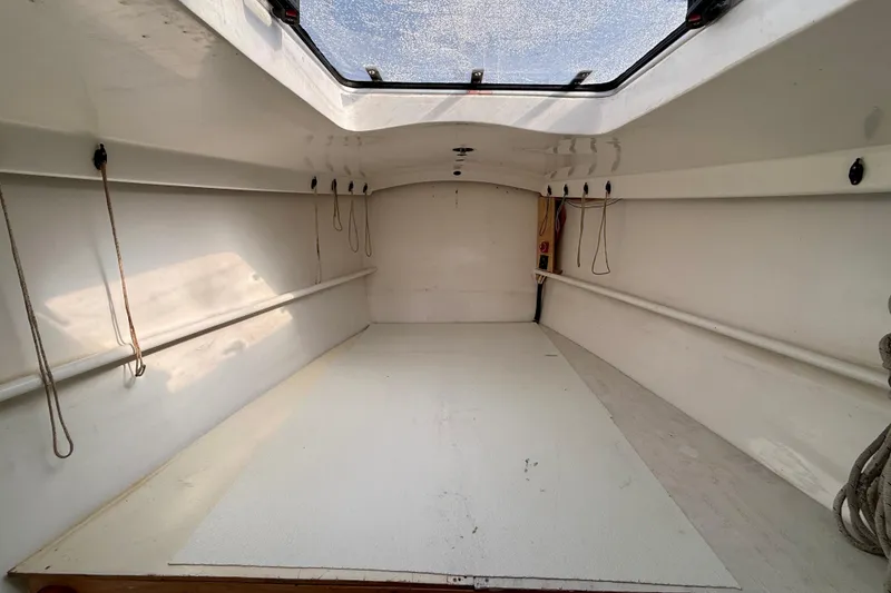 Slide: The Image of Interior of a 1985 MacGregor 65 sailboat, featuring a spacious, white cabin with ropes. - 30