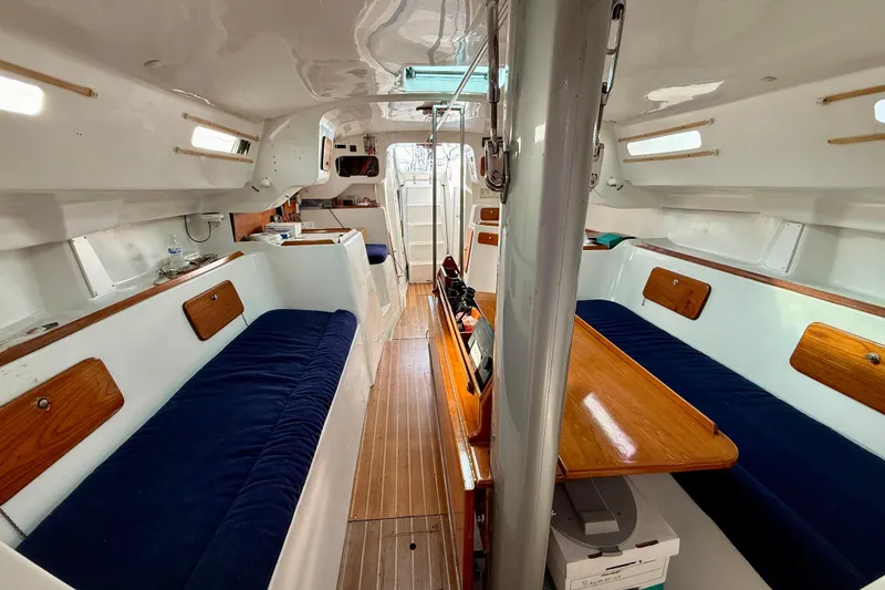 Slide: The Image of Interior of a 1985 MacGregor 65 sailboat with blue seating and wooden accents. - 31