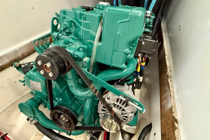 Slide: The Image of Engine of a 1985 MacGregor 65 sailboat, featuring a green motor and belt system. - 36