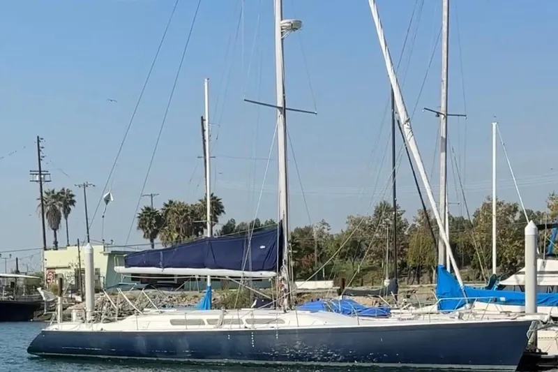 Slide: The Image of 1985 MacGregor 65 sailboat docked, featuring blue sails and a sleek design. - 38
